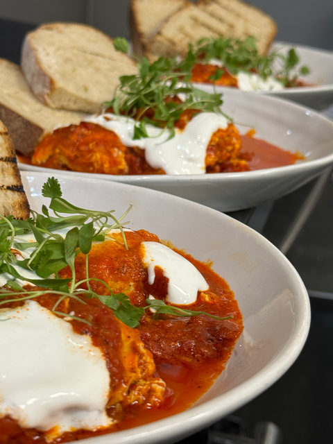 Plated meatballs in tomato sauce with burrata and grilled bread